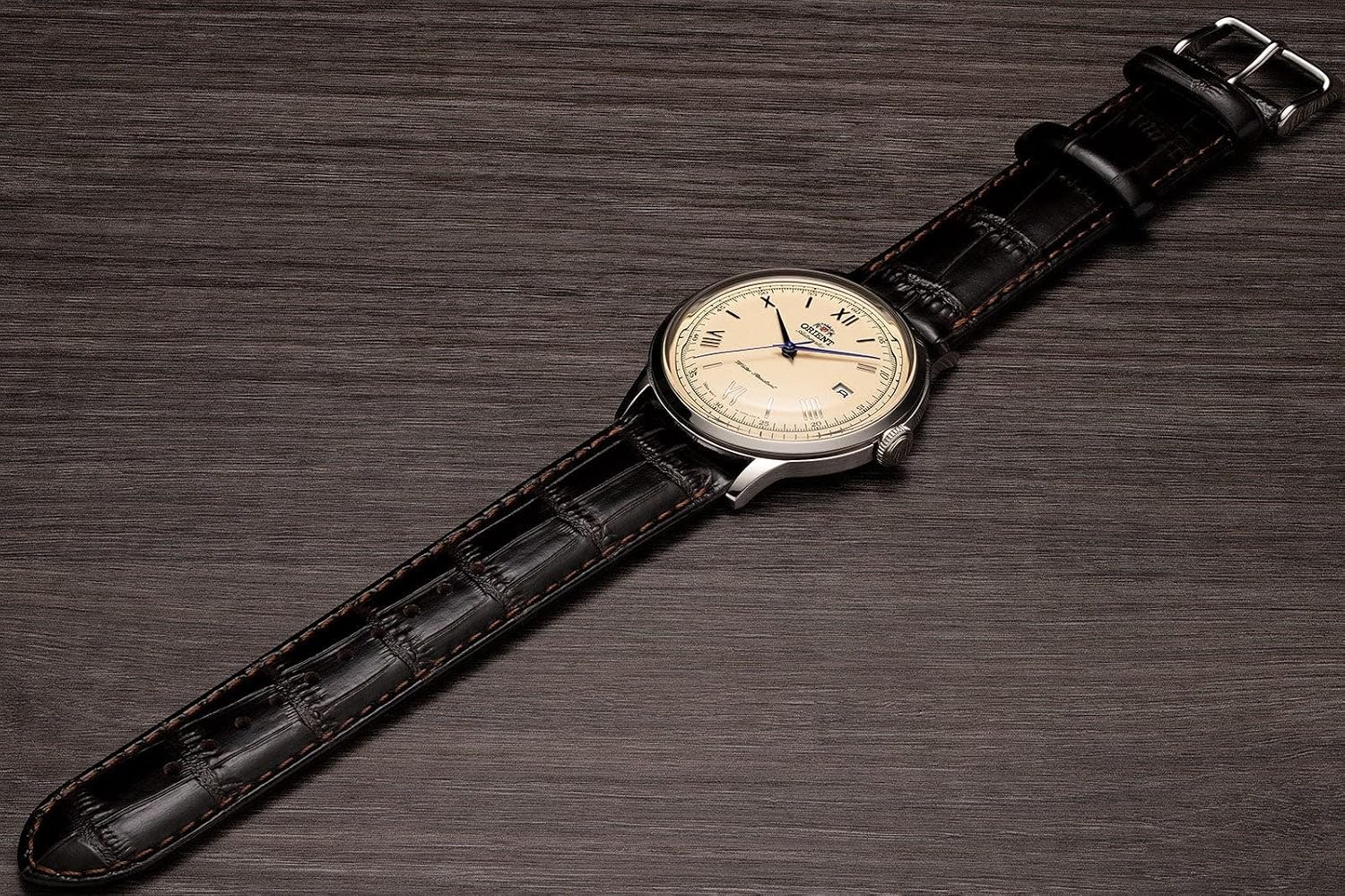 Orient Bambino Version 2 full watch with brown leather strap on wood surface